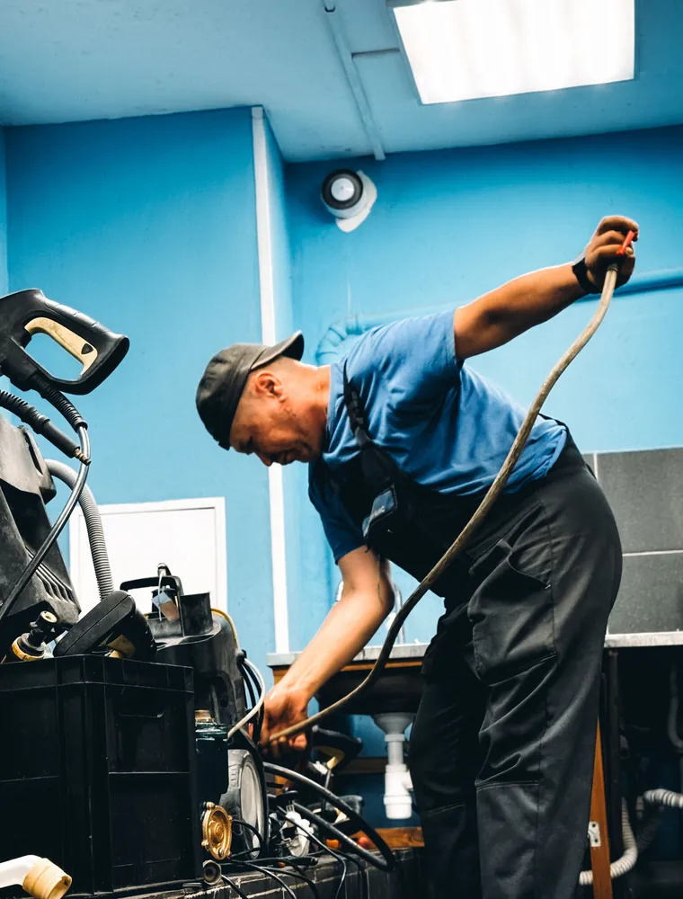 Plumber in a blue uniform working over a pump in a workshop