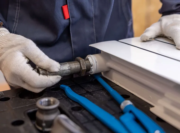 Gloved hands fitting a radiator pipe connection