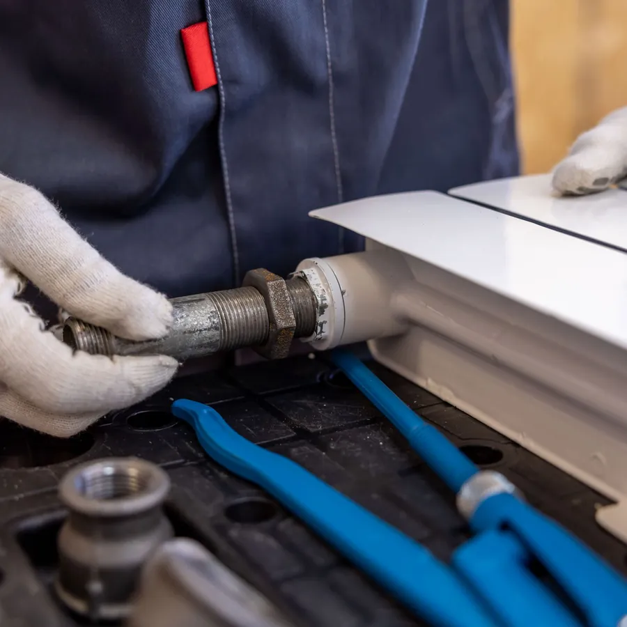 Gloved hands fitting a radiator pipe connection