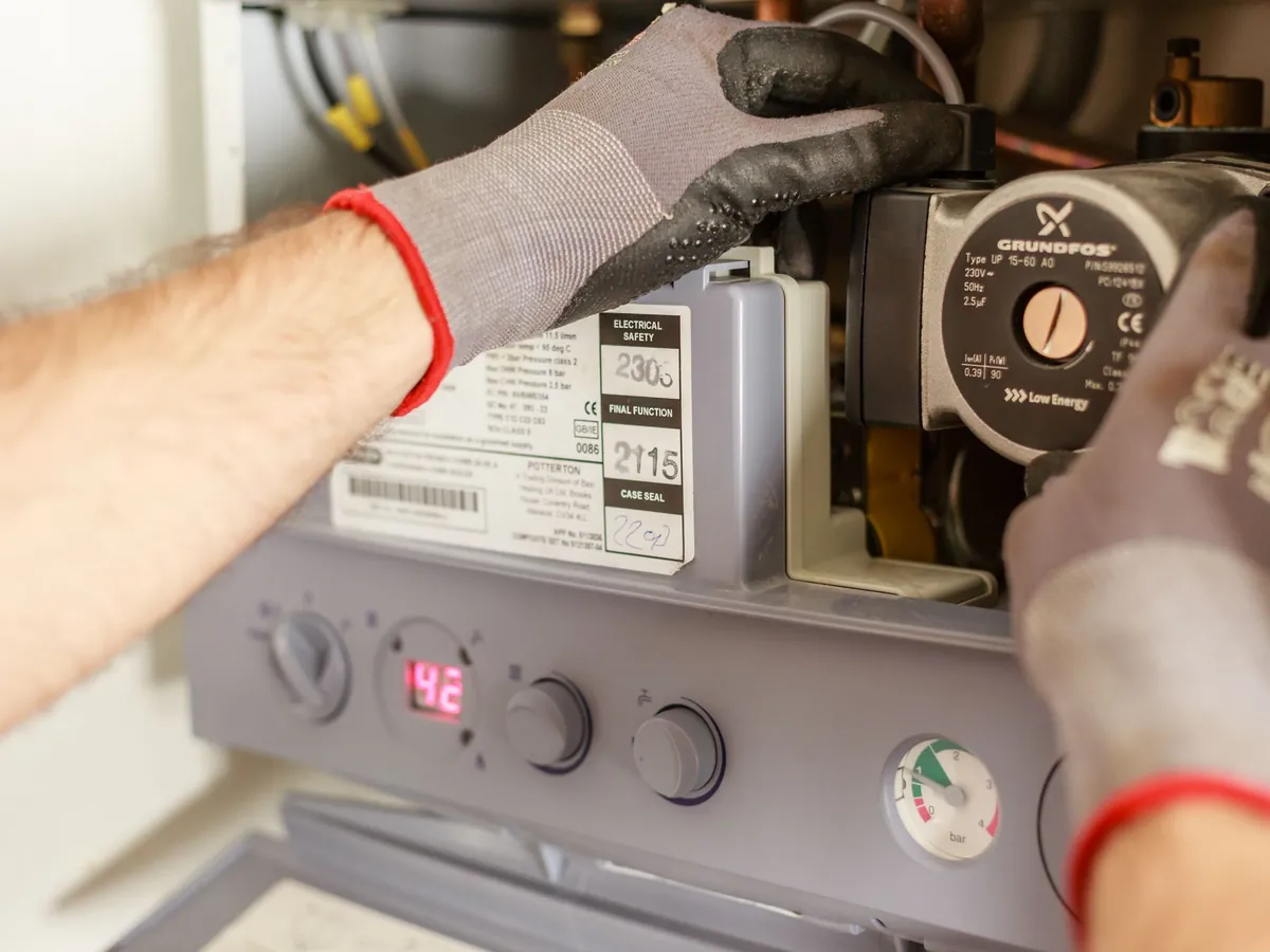 Gloved hands working on a boiler pump