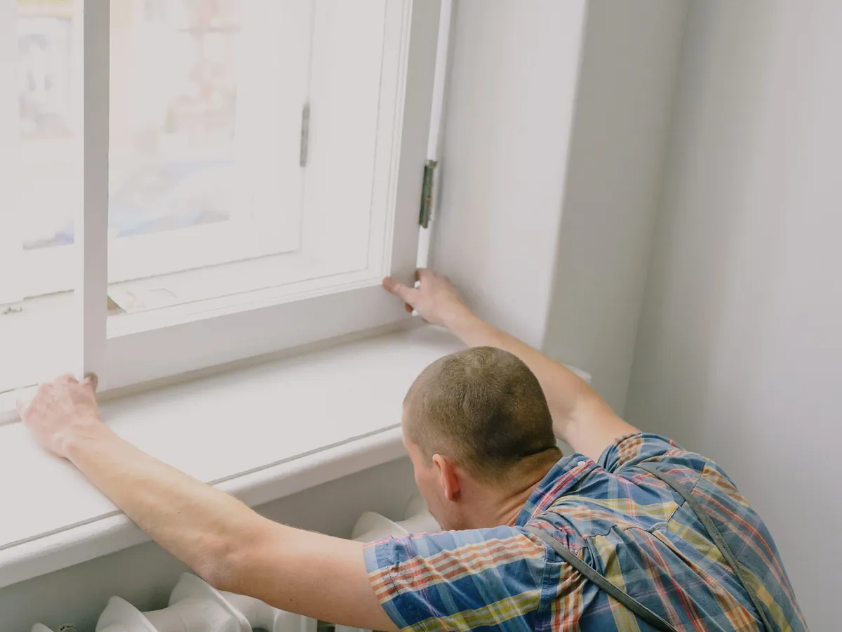 Fitter positioning a radiator beneath a window