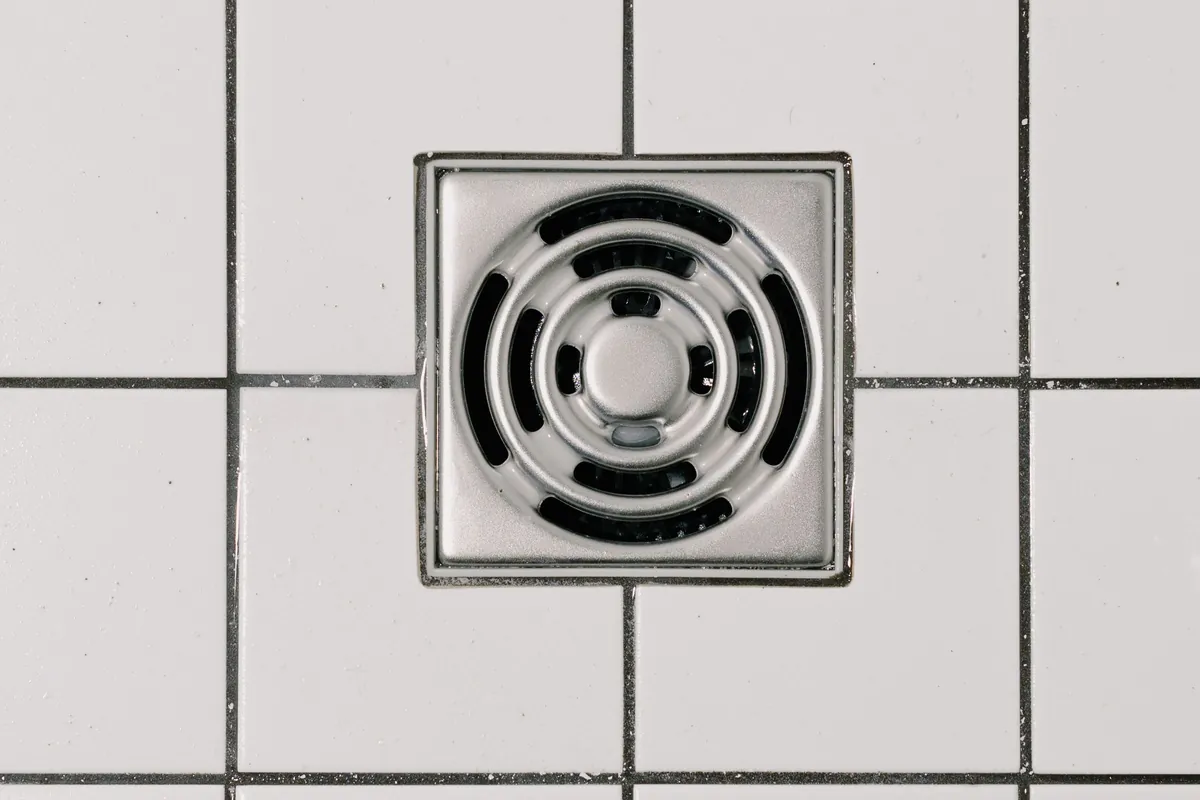 Square shower drain set in white tiles